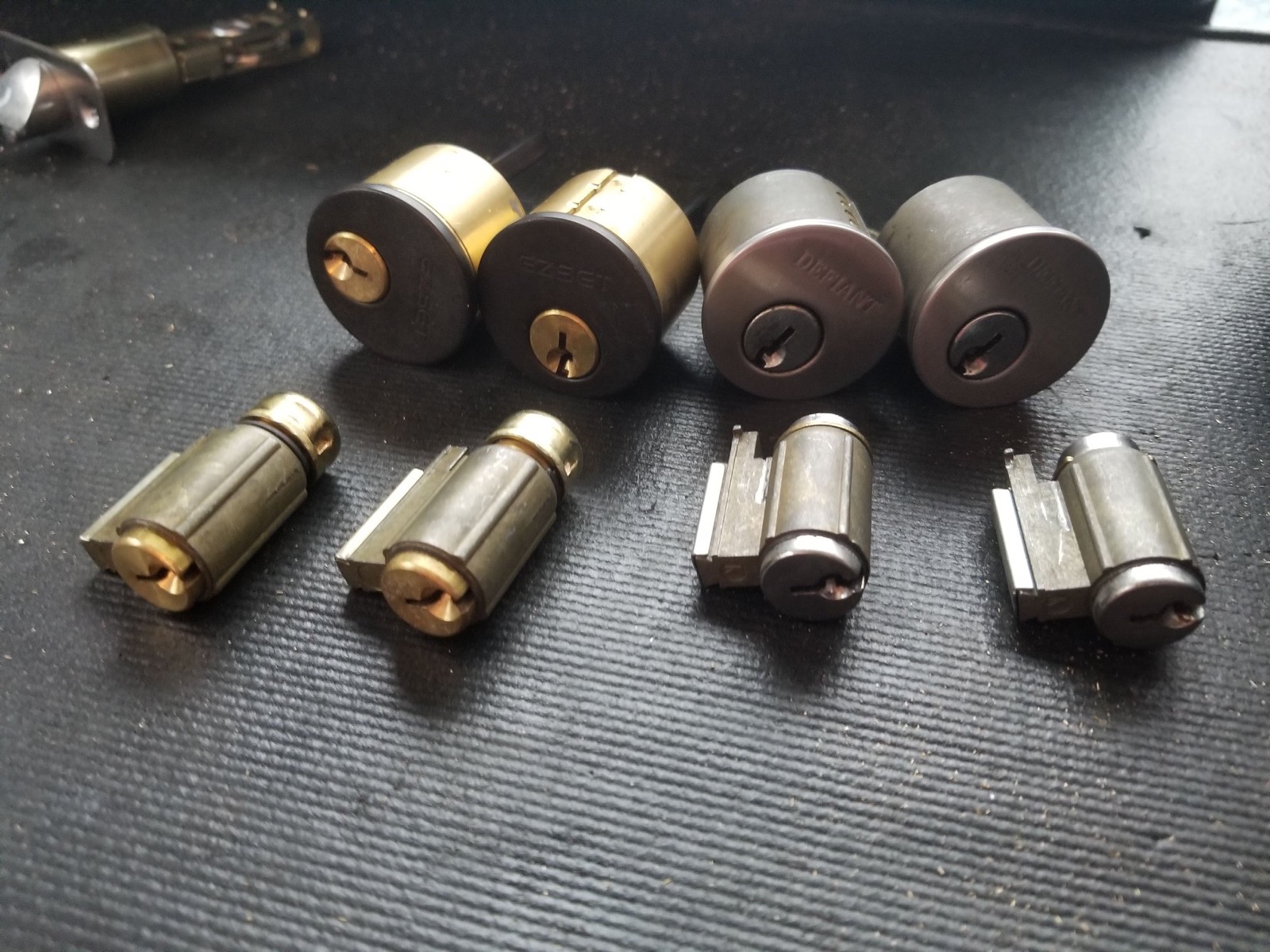 Brass rim and mortise lock cylinders lined up on a work mat
