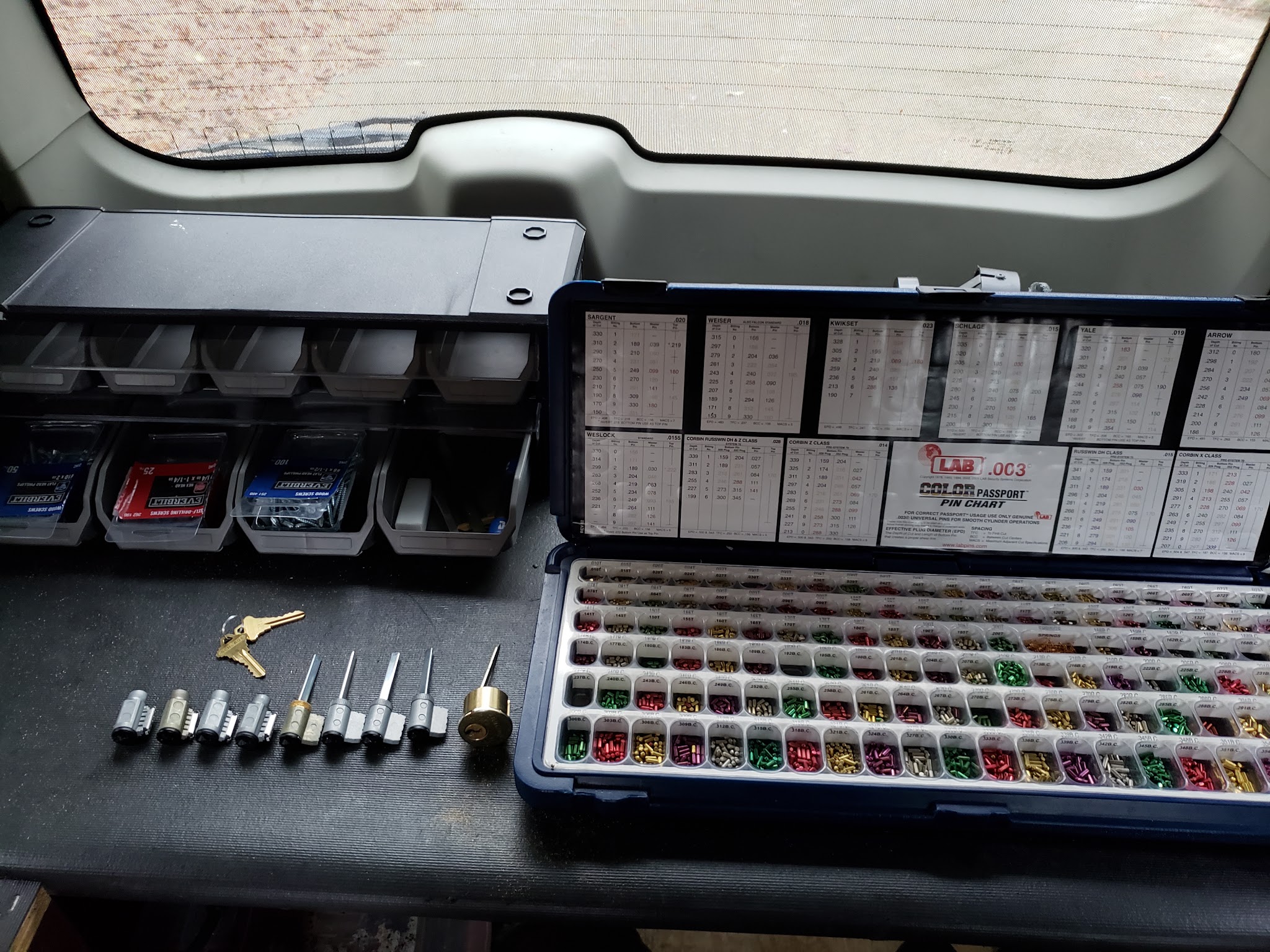 Rekeying pinning kit with key pins, cylinders and keys laid out in the back of the van