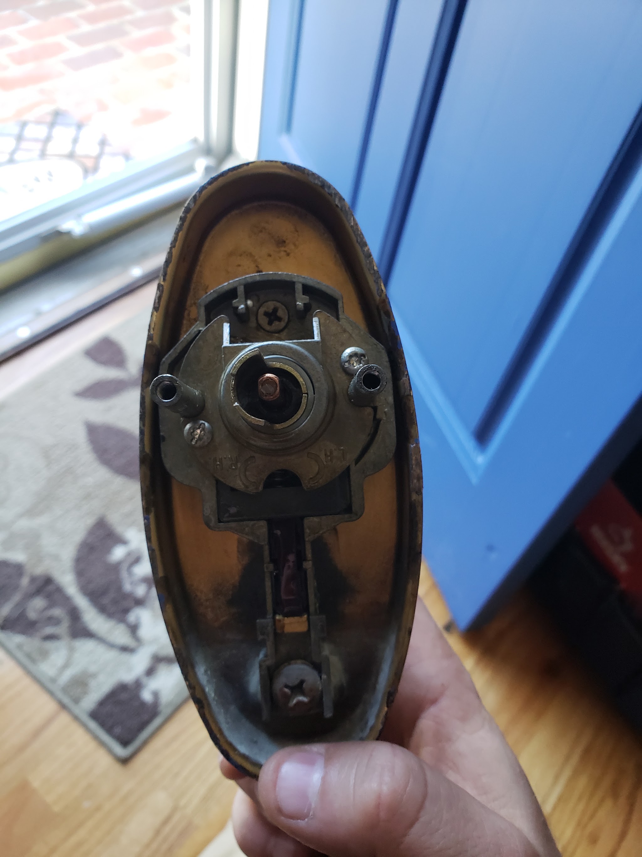 An opened knob lock held in hand, showing the lock mechanism