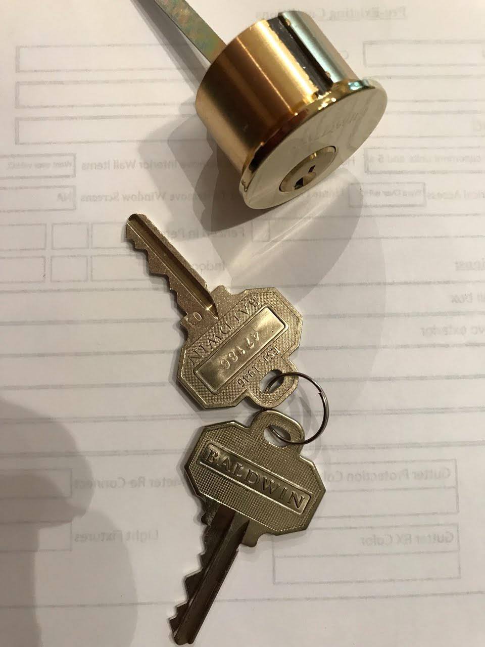 A new brass rim cylinder with two freshly cut keys on paperwork